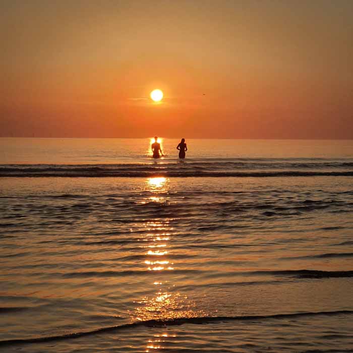 Castricum aan Zee beach - Two lovers meeting sunset in the water - Discover True Netherlands