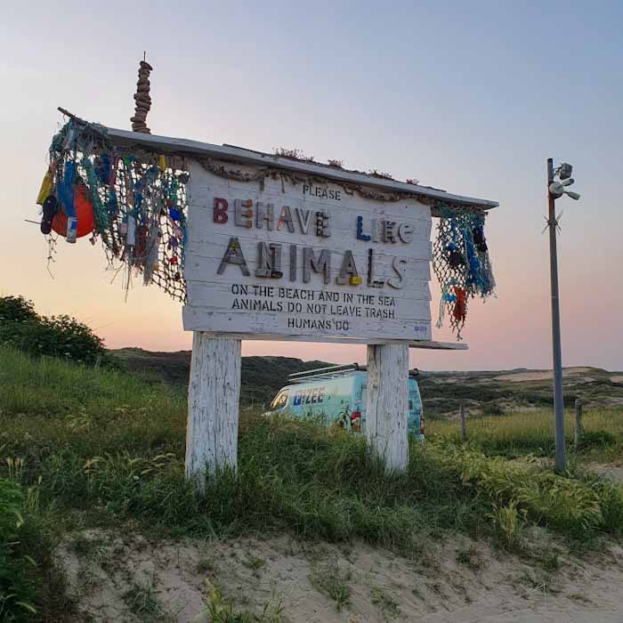 Castricum aan Zee beach - Wooden sign saying Behave like an animal and dont leave garbage - Discover True Netherlands
